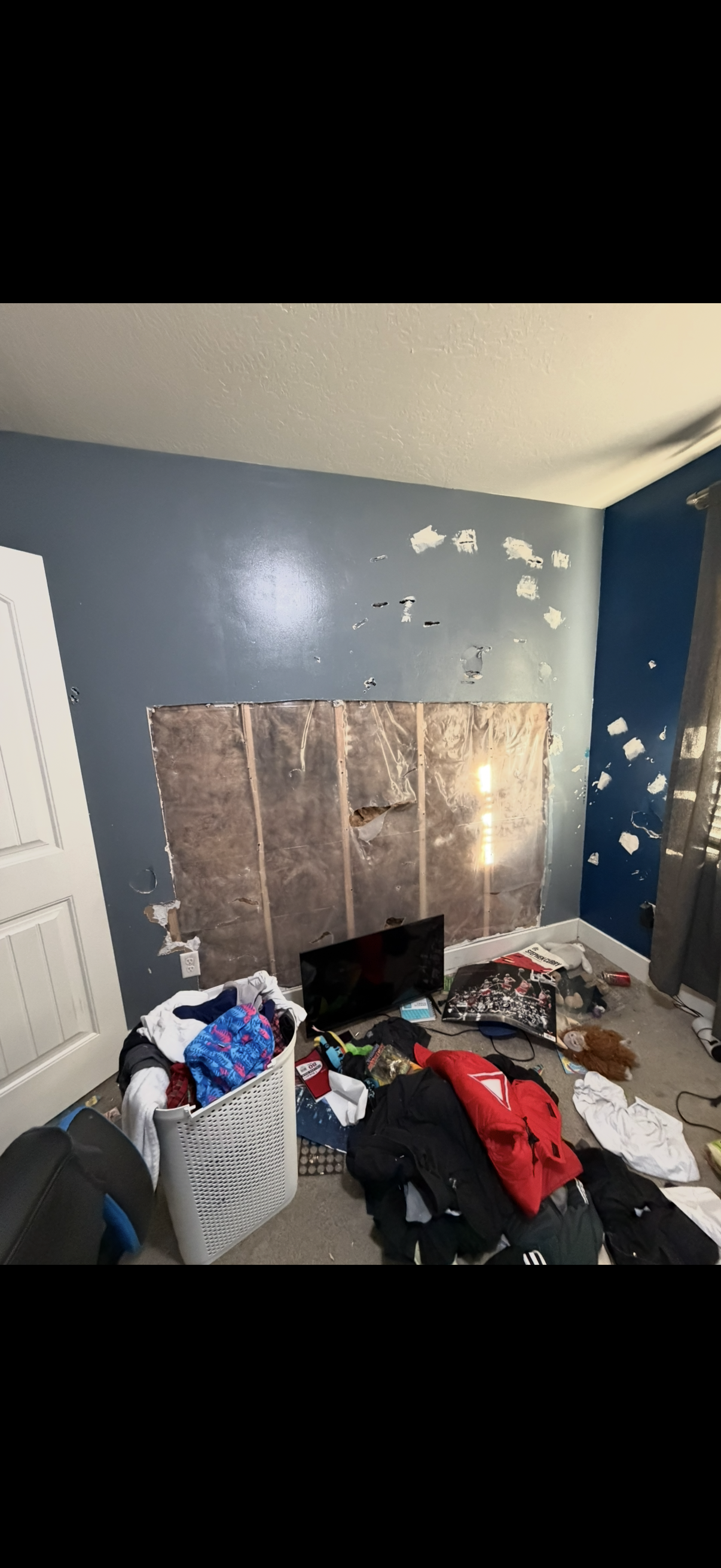 bedroom wall before repair — large section of drywall missing with multiple holes in Utah County
