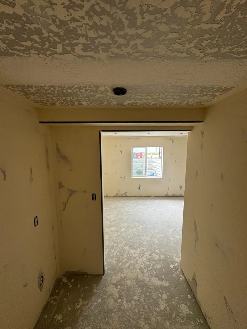Doorway into a basement bedroom with a knockdown ceiling and walls ready for paint