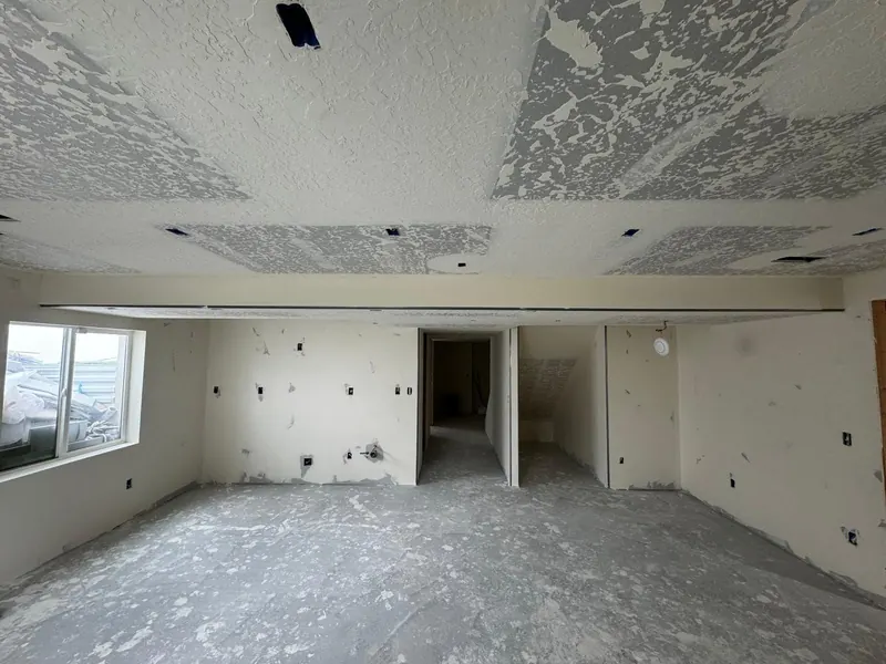Basement with a long soffit and a knockdown ceiling, walls sanded and ready for primer