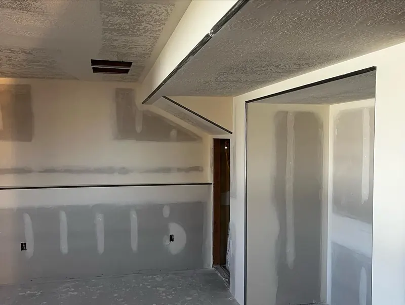 Basement drywall with soffits and a doorway wrapped in metal trim, walls taped and mudded under a knockdown ceiling