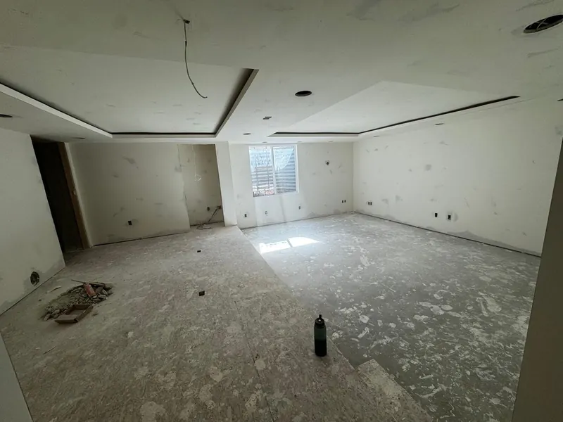 Basement room with a tray ceiling built in drywall, walls ready for paint