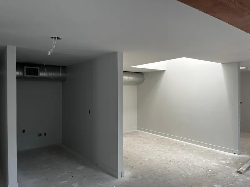 The same commercial space finished: drywall partitions painted, with baseboards and the skylight well complete