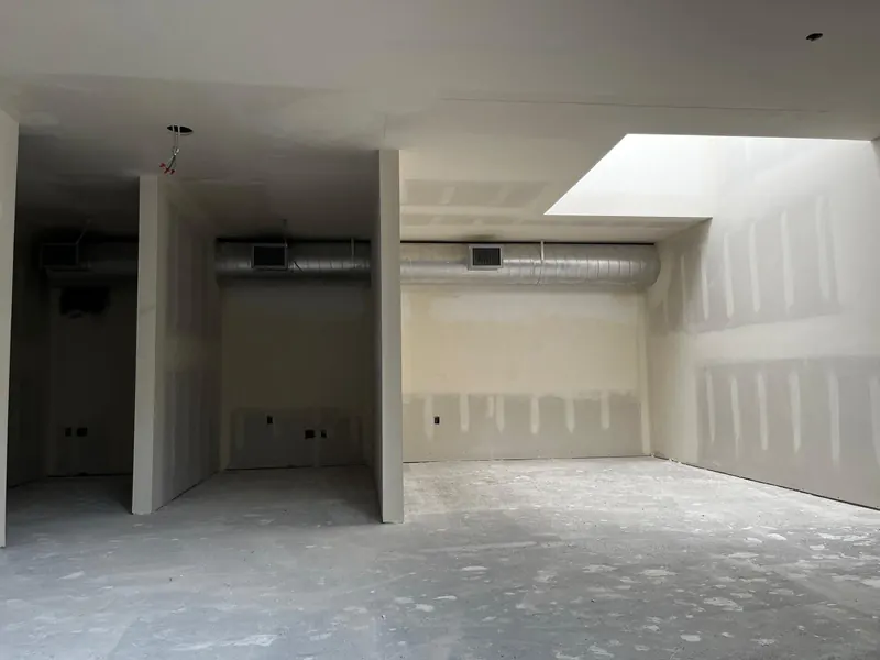 Commercial space with new drywall partitions taped and mudded around exposed ductwork and a skylight well