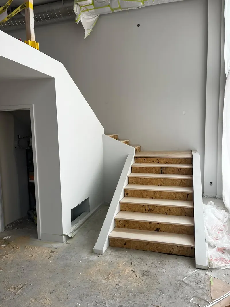 Stairwell drywall finished and painted with clean lines along a new stair