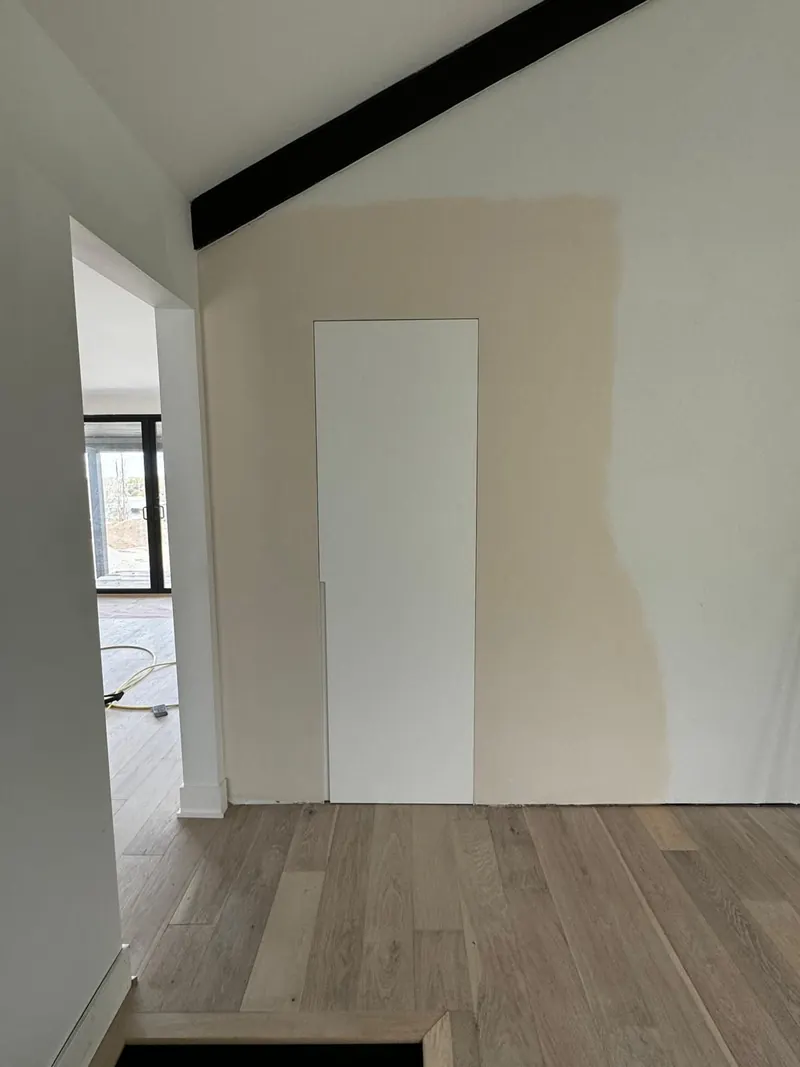 Drywall patched and primed around a new flush-mounted hidden door, ready for paint